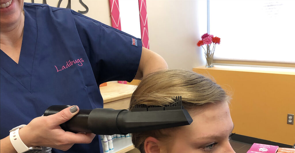 A girl getting lice treatment with the Zyma Air Therapy device